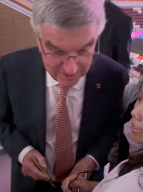 巴赫主席很认真给孙颖莎球迷签名，签在了“莎莎下巴”上