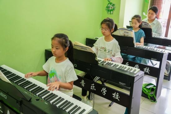 2025年7月22日，在山东省乐陵市市中街道春之声培训中心，孩子们在练习电子琴。