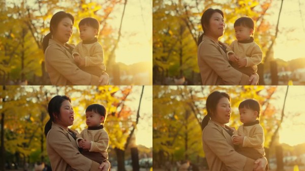 亚洲母子亲密关系，母亲与幼儿的照顾。冬季公园中的真实家庭。夕阳下，他们微笑着，幸福地转身，享受快乐的
