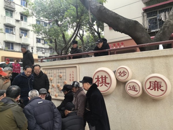 民主村社区居民围坐下棋。徐雯瑄摄