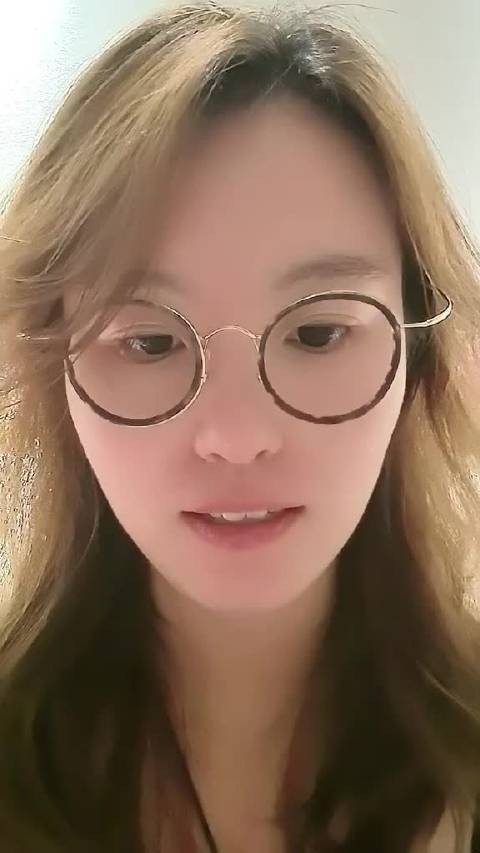 傅园慧一位戴眼镜的女性正在看手机或屏幕，表情专注。
