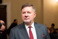 A headshot of Oklahoma attorney general Gentner Drummond, a white man wearing a business suit and red tie