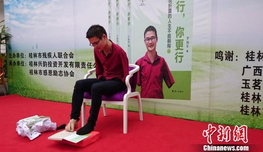 罗相军用脚执笔为读者签名。　欧惠兰　摄