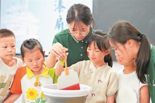 日前，铜仁市石阡县困牛山红军学校，大学生志愿者和孩子们在制作漆扇。申逸恺 摄