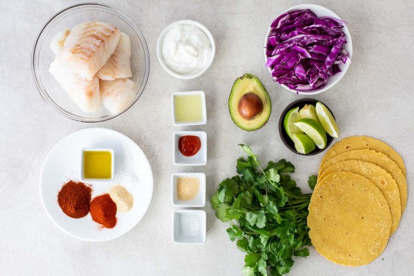 Ingredients for fish tacos recipe on a white countertop.