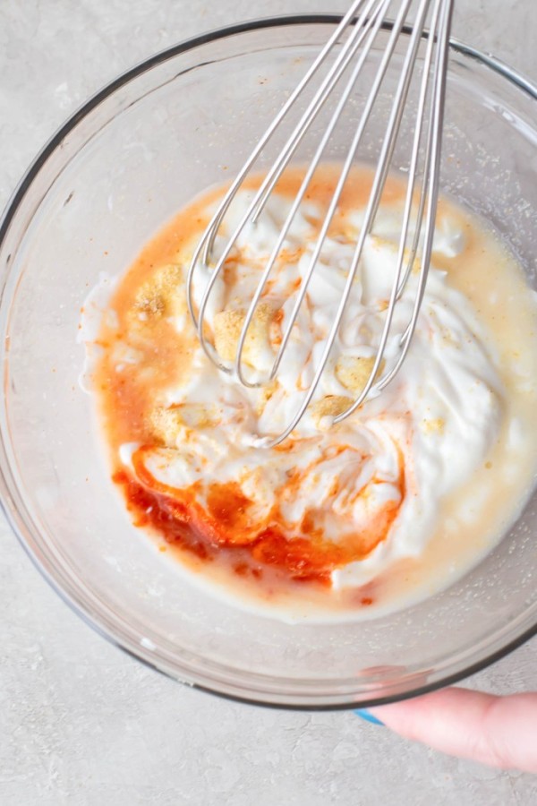 Mixing together sauce ingredients in a bowl with a whisk.