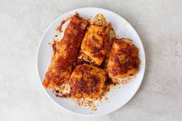 Seasonings rubbed onto 4 raw pieces of white fish.