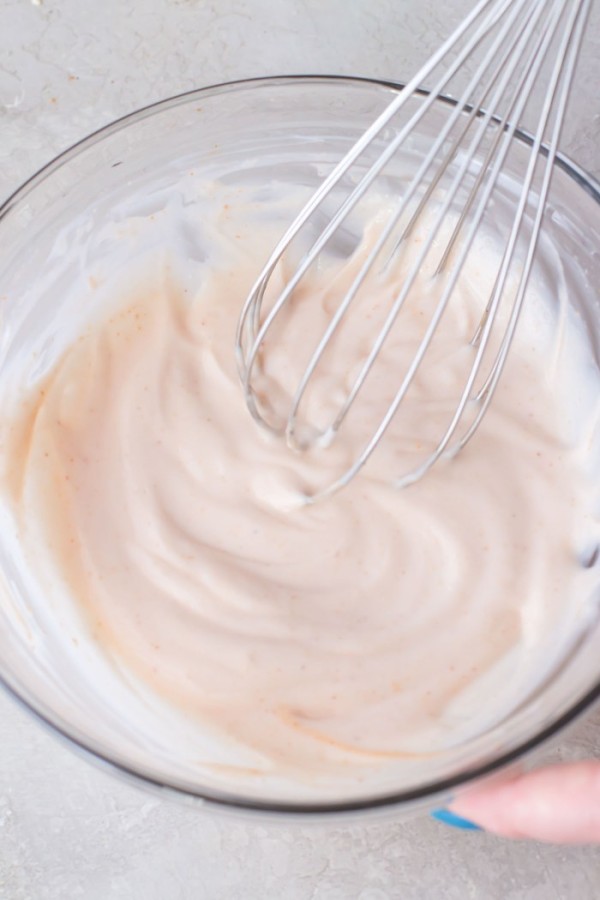 Fish taco sauce in mixing bowl with a whisk.
