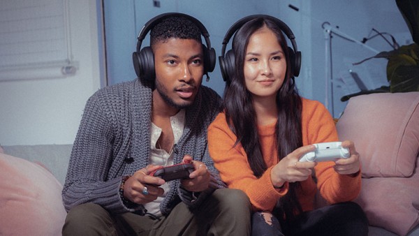 兩個人拿著 Xbox 控制器，一起玩多玩家遊戲。