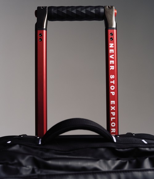 The top of black rolling luggage, you can read “NEVER STOP EXPLORING” on the handle.