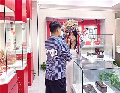 今年七夕，在呼和浩特市玉泉区婚俗博物馆，新人试戴凤冠。