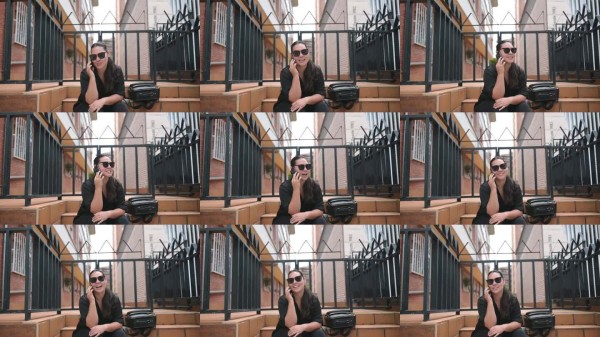 女性在城市建筑旁放松或接电话，进行户外旅行或酒店预订。女游客在城市中进行手机通话，计划旅行、休闲或旅