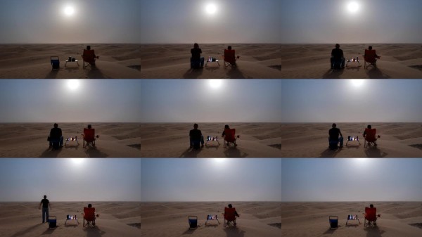 情侣旅行者在沙漠露营,伴随着月亮的移动在沙丘上放松。