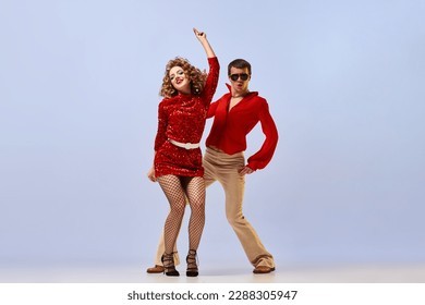 迪斯科舞厅舞蹈。一对舞者身着亮丽的复古时尚服装，在淡紫色背景上翩翩起舞，姿态生动传神。音乐、艺术、复古的概念。