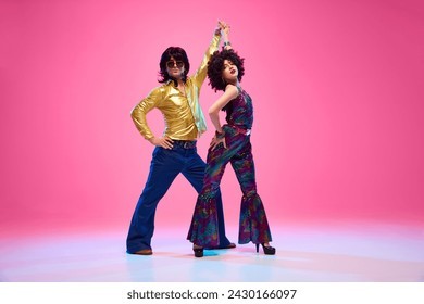 一对身着亮丽服装的活力舞者在粉色渐变背景的摄影棚里翩翩起舞，展现迪斯科舞步。这体现了美国文化、20世纪70年代和80年代的时尚、音乐以及不同时代的对比。