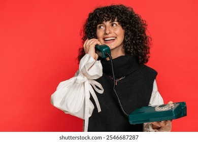 嘿，你，给我打电话。一位卷发的白人年轻女子正在使用80年代的老式有线座机通话，这是在推销在线购物服务。女孩在红色背景下显得格外醒目。