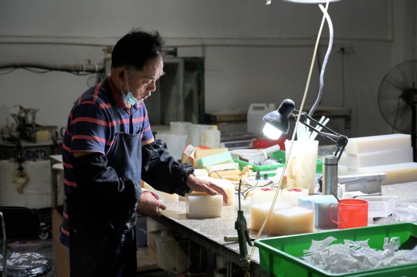 生产车间里，老师傅正在手工从模具中取出雕像分件。