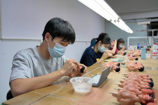 手办模玩生产车间里，企业培训年轻人参与涂装工作。