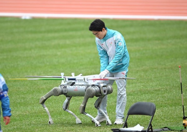 11月19日，志愿者从机器狗上取下标枪。当日，第十五届全国运动会田径项目女子七项全能标枪比赛在广州举行。新华社记者 邓华 摄