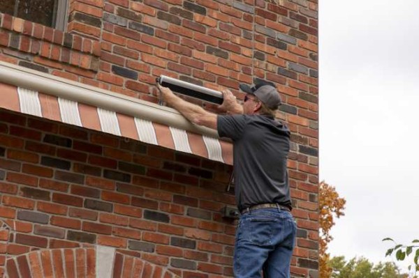 Person mounting a solar panel above a home awning