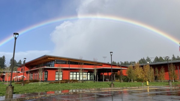 A rainbow above the red-colored building of Vashon High School on Vashon Island