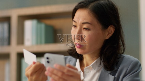 亚洲女性购物者，快乐的消费者，满意的女商人，在线购物，办公室使用手机支付，互联网银行信用卡付款。照片摄影图片