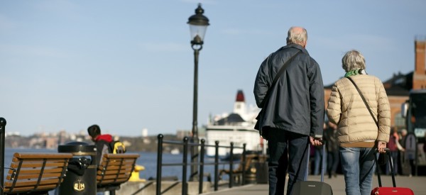 一对年龄较大的夫妇拉着行李箱漫步在瑞典斯德哥尔摩