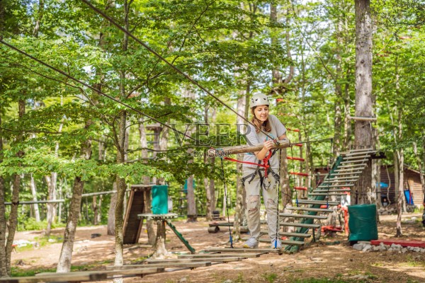 快乐的女性女孩在森林中通过安全链接的登山扣在树与树之间滑行攀爬，体验极限滑索冒险公园的乐趣。家庭周末儿童活动概念，坐在咖啡桌旁的一个不满的女孩的肖像。照片摄影图片
