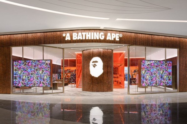 a fashion model showcasing a hooded sweatshirt featuring a camouflage pattern and various branding elements