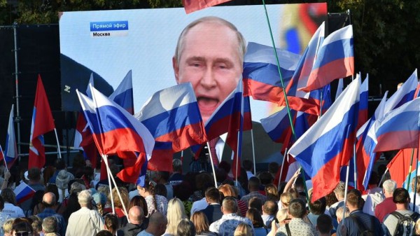 People in Crimea watching a speech by Vladimir Putin in 2022. Pic: AP
