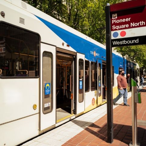 a person gets off the light rail train at the Pioneer Square stop with its iconic red brick walkway