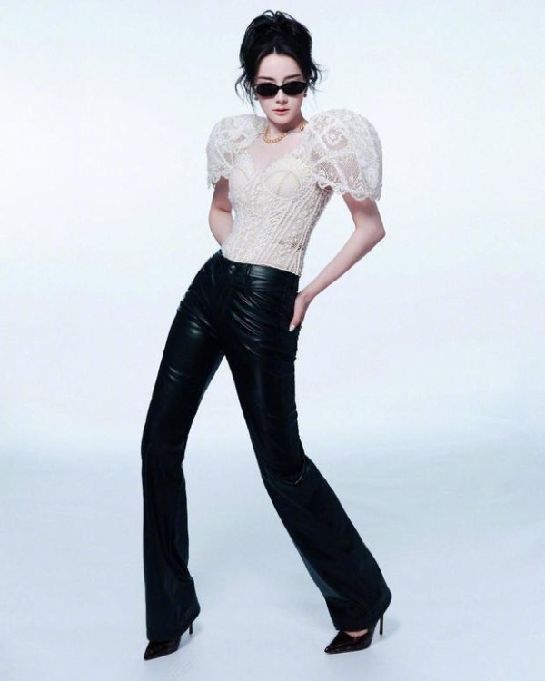 迪丽热巴白蕾丝泡泡袖上衣搭配黑皮裤与墨镜，双手插兜，酷飒气场拉满。