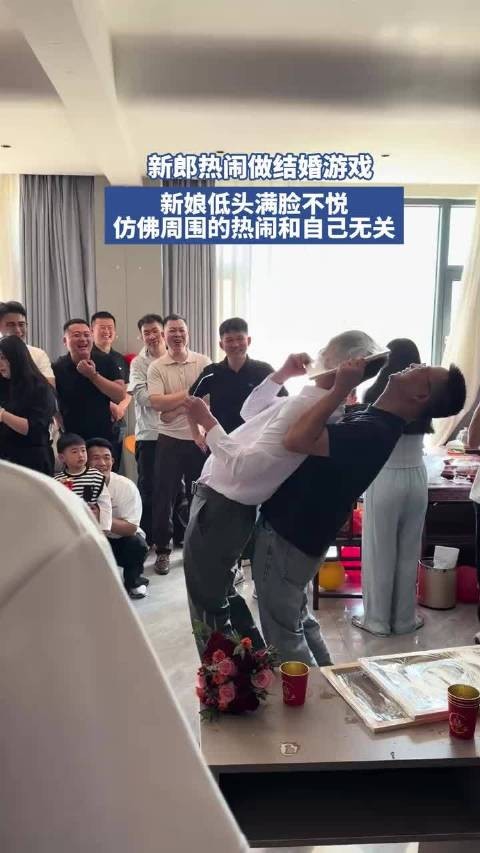 新郎热闹做结婚游戏，新娘低头玩手机仿佛周围的热闹和自己无关