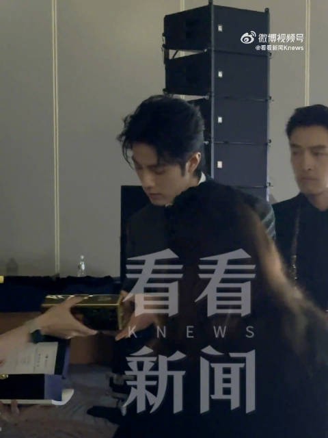 肖战双手将奖杯递给同伴