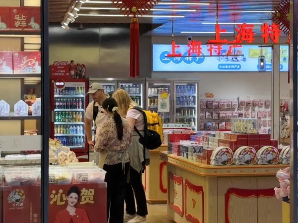 国庆假期,外国游客在上海虹桥火车站内购买上海特产。新华社发(陈晨 摄)